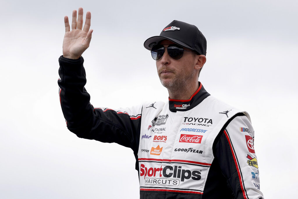 Denny Hamlin, driver of the #11 Sport Clips Haircuts Toyota, waves to fans as he walks onstage during driver intros prior to the NASCAR Cup Series Hollywood Casino 400 at Kansas Speedway on September 27, 2026 in Kansas City, Kansas. (Photo by Sean Gardner/Getty Images)